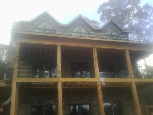 Dormers and porch framing on a large log home under construction — Roof Coating work by our crew in Medina